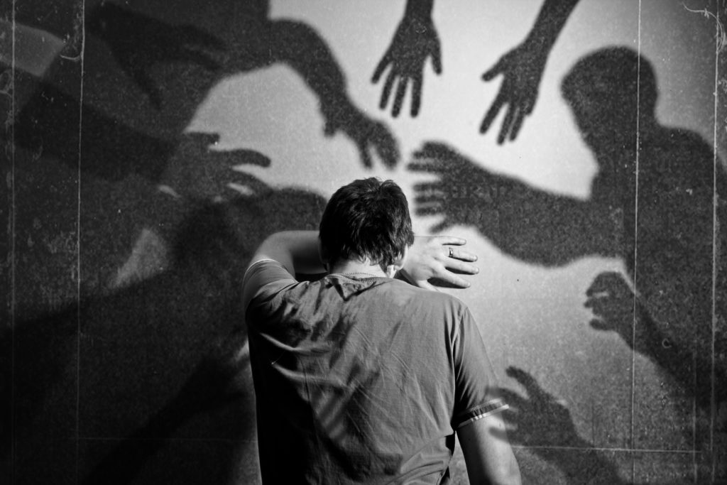 A young man leaning on the wall scared from shadow